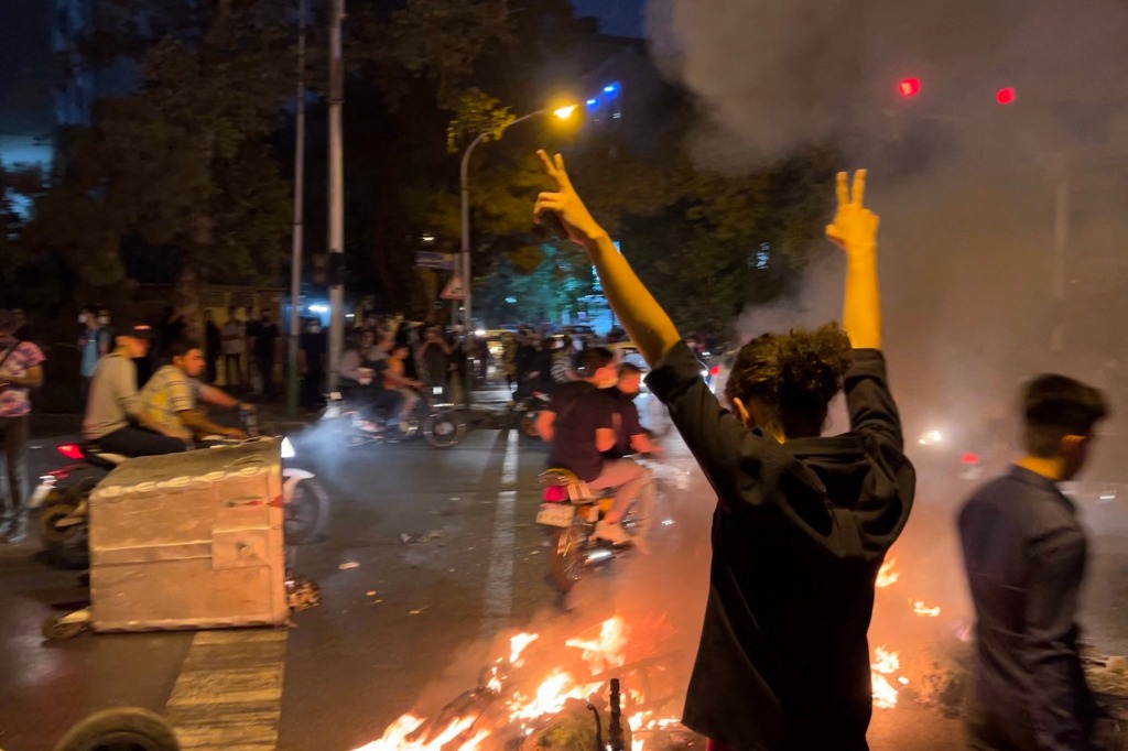 A picture obtained by AFP outside Iran shows shows a demonstrator raising his arms and making the victory sign during a protest for Mahsa Amini.