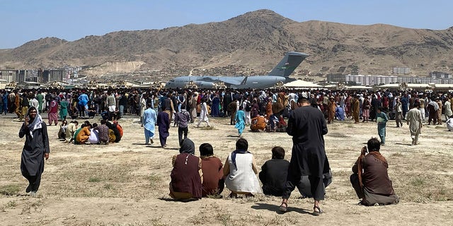 Hundreds of people gather near a U.S. Air Force C-17 transport plane at the international airport in Kabul, Afghanistan, on Aug. 17, 2021.