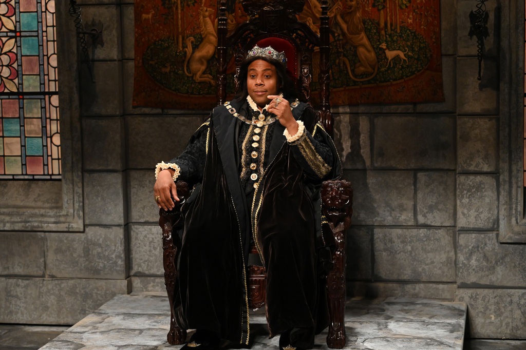 Kenan Thompson sits on a throne wearing a crown and long robe. 
