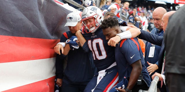 New England Patriots quarterback Mac Jones is helped off the field after suffering a leg injury with less than two minutes to play in the second half of a game against the Baltimore Ravens, Sunday, Sept. 25, 2022, in Foxborough, Mass.