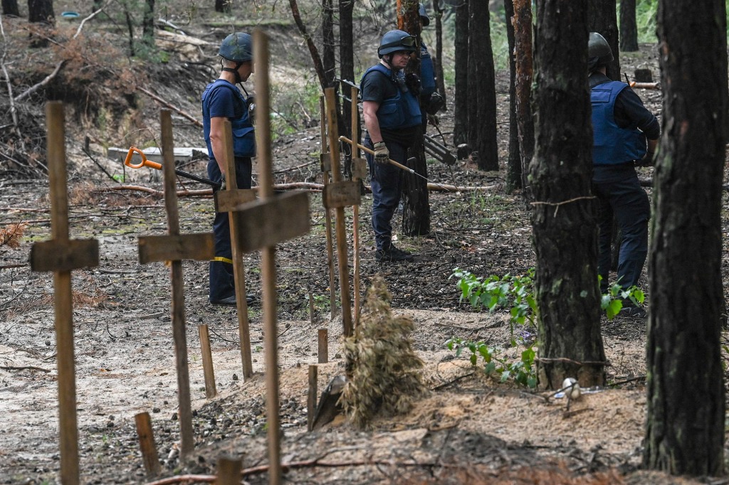 Ukrainian servicemen search for land mines at a burial site in Izium, Ukraine.