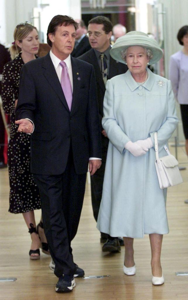 Paul McCartney shows Queen Elizabeth II his paintings during a visit to the Walker Art Gallery in Liverpool on July 25, 2002.