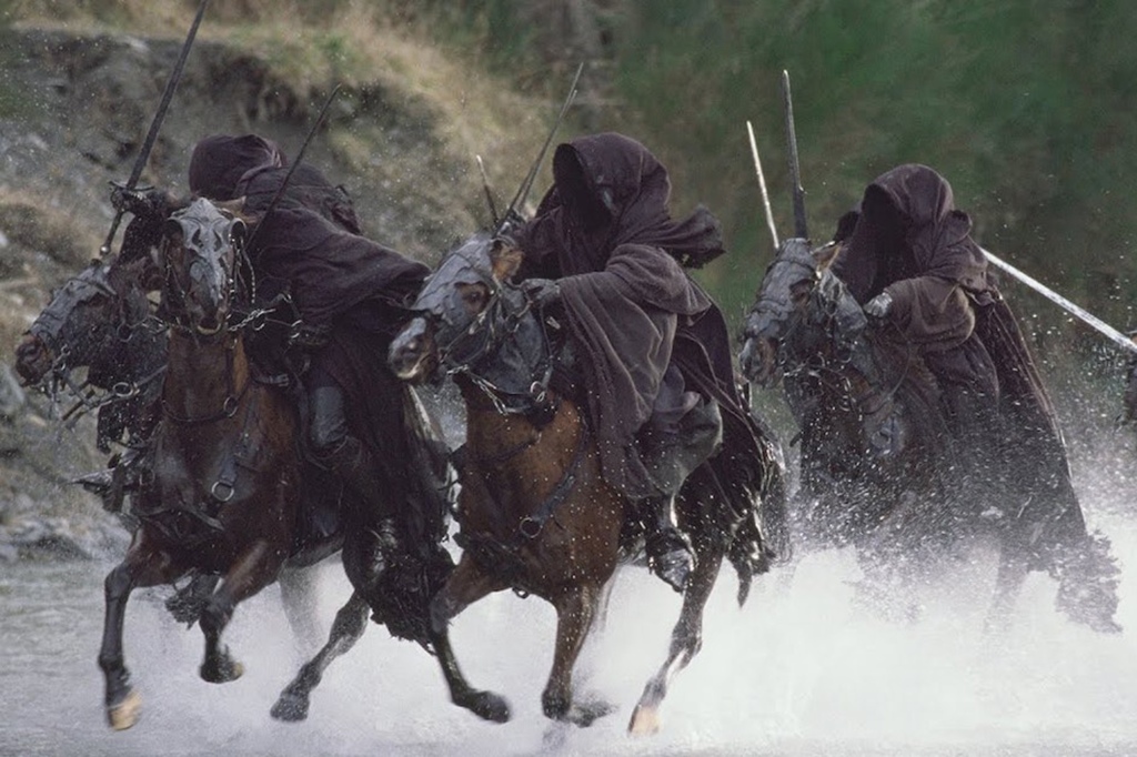 Hooded figures cloaked in black riding horses. 