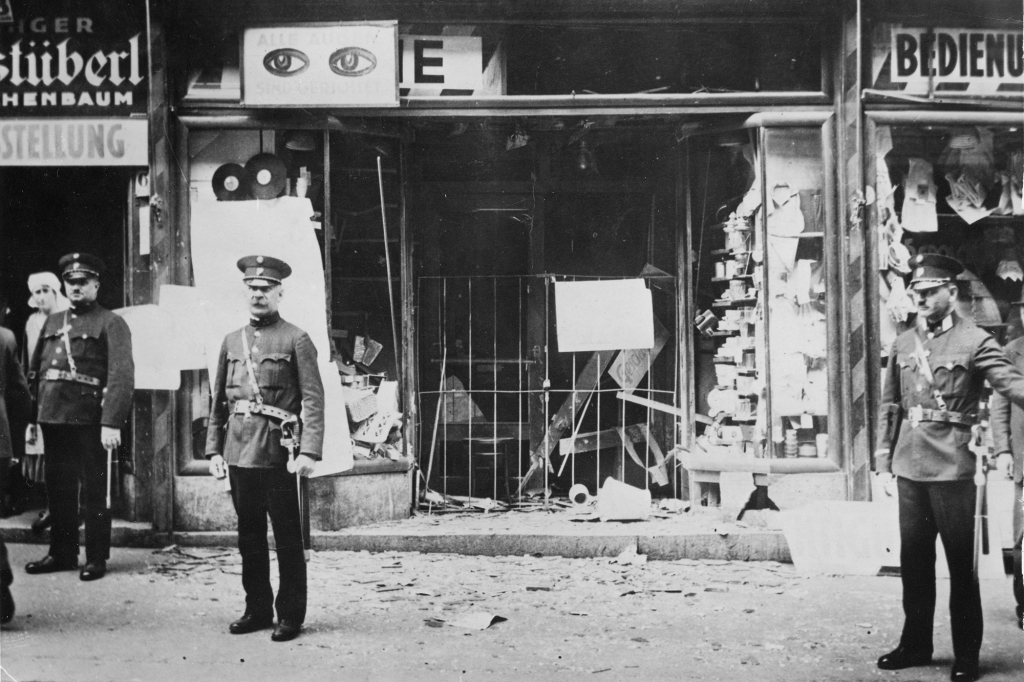 Uniformed officers stand outside a Jewish-owned shop in Vienna after the widespread destruction and violence of Kristallnacht on November 10, 1938. 