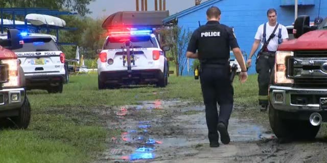 An Orlando police officer walks toward a firefighter as first responders search for a rower who went missing following a lightning strike on Lake Fairview.