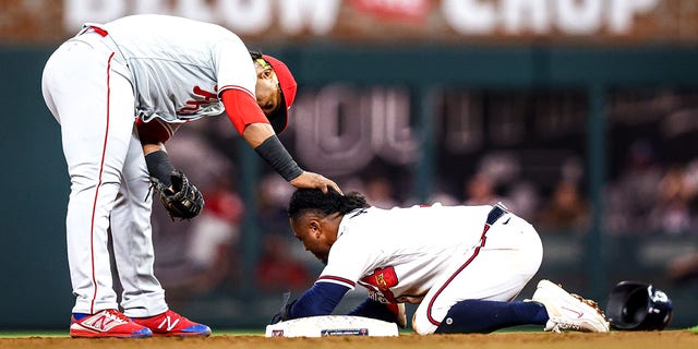 Jean Segura #2 of the Philadelphia Phillies checks on an apparently injured Ozzie Albies #1 of the Atlanta Braves after Albies slid into second base in the bottom of the fourth inning of a game at Truist Park on Sept. 17, 2022 in Atlanta, Georgia.