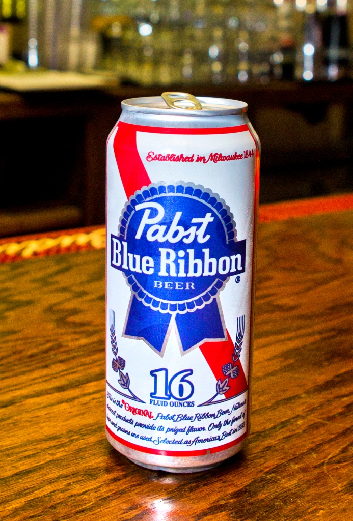 Pabst Blue Ribbon tall boy can sits on a wooden bar.