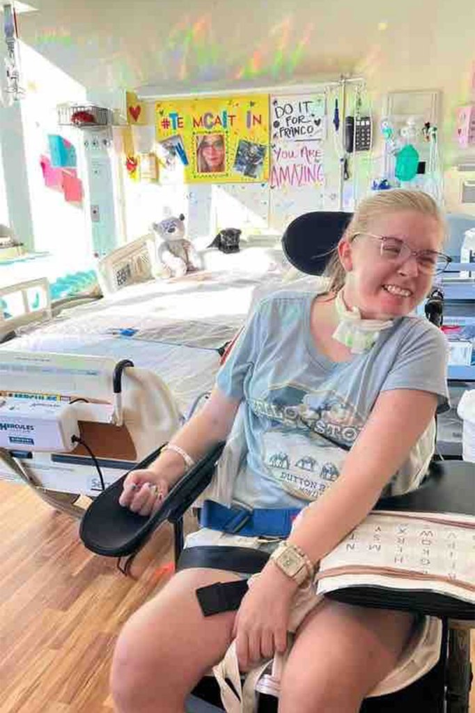 Caitlin Jensen smiling in a wheelchair in the hospital.