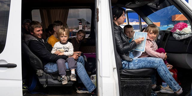 People with children wait after arrival from the Ukrainian city of Tokmak at a center for displaced people in Zaporizhzhia, Ukraine, Monday, May 2, 2022. 