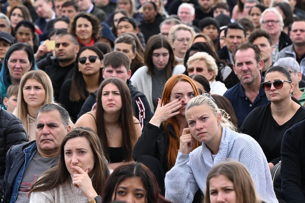 Members of the public cry as they watch the State Funeral Service of Britain's Queen Elizabeth II on a large screen in Hyde Park, London, on September 19, 2022. 