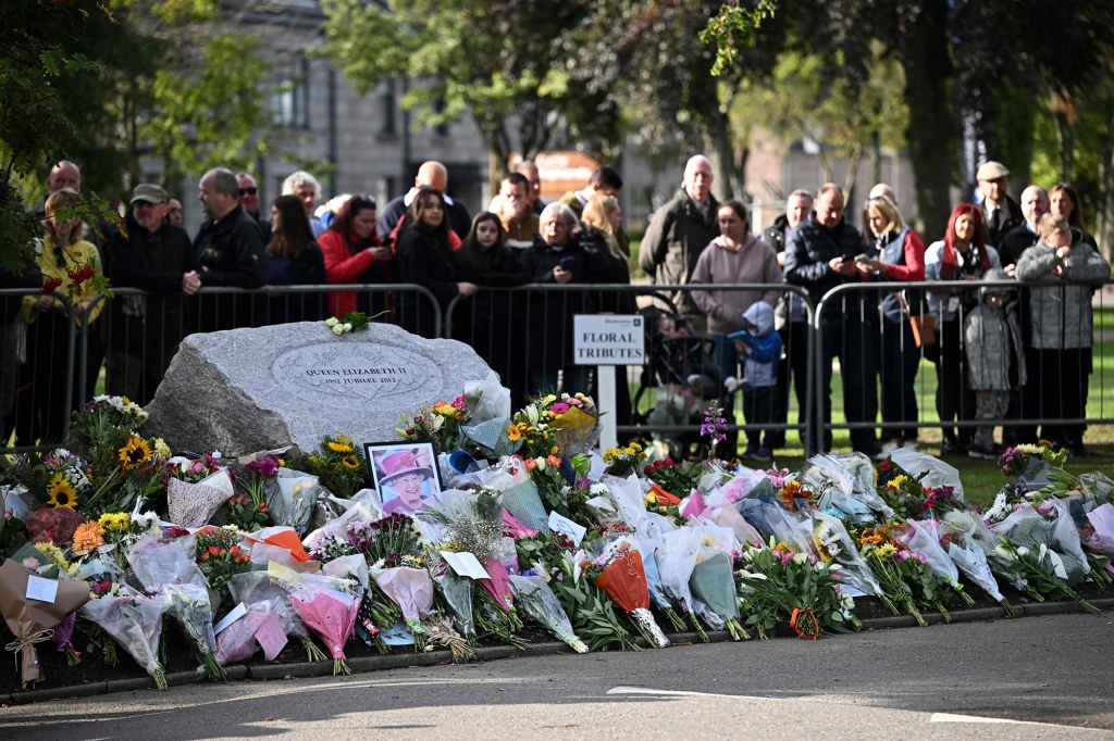 Members of the Public gather by a makeshift memorial to pay respects as they wait for the hearse carrying the coffin of Queen Elizabeth II to pass through Ballater, on Sept. 11, 2022.