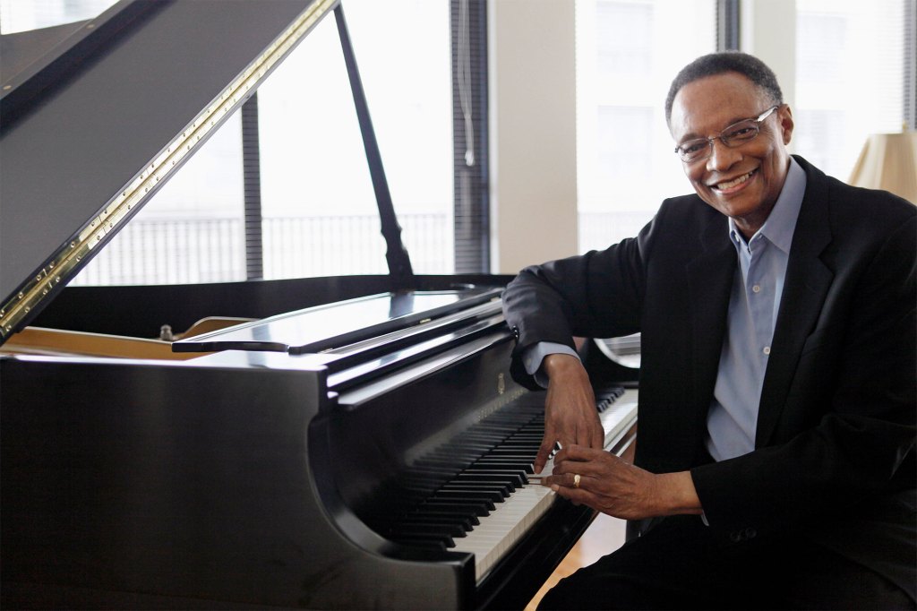 Ramsey Lewis poses next to a piano.