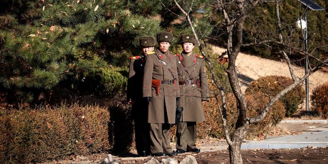 North Korean soldiers looking toward the South at the DMZ. South Korea is reportedly broadcasting news about the defector through loudspeakers.