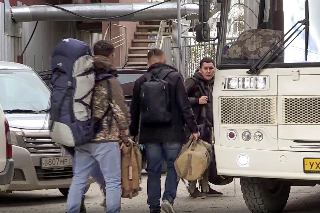 In this image taken from video, Russian draftees walk to take a bus to be sent further to the military units of the Eastern Military District, in Yakutsk, Russia, Friday.