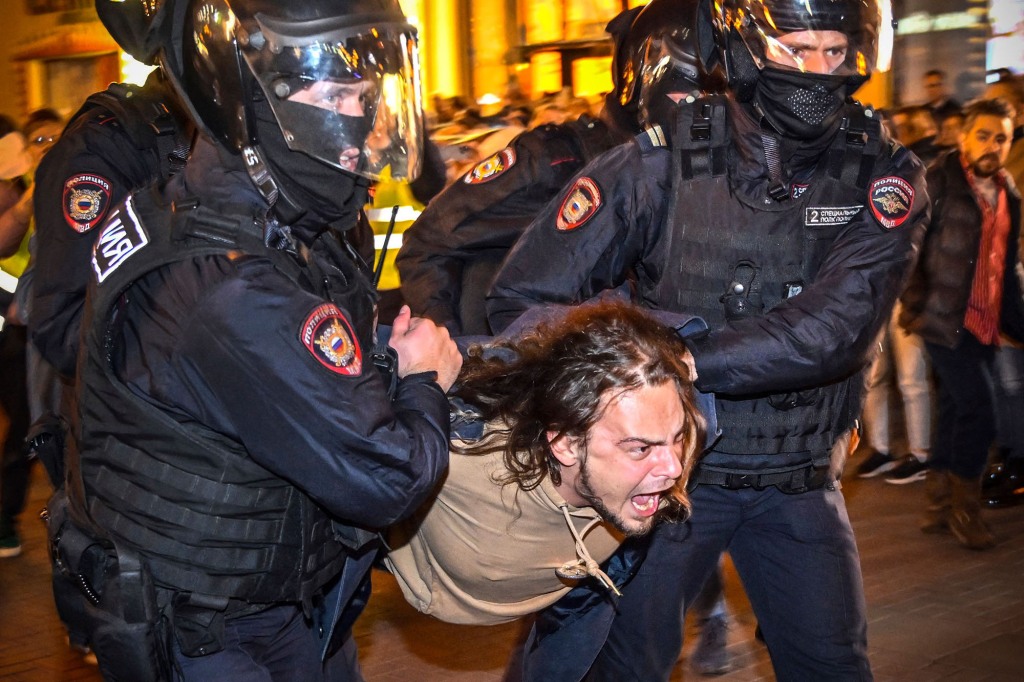 Police officers detain a man protesting Russia's mobilization.