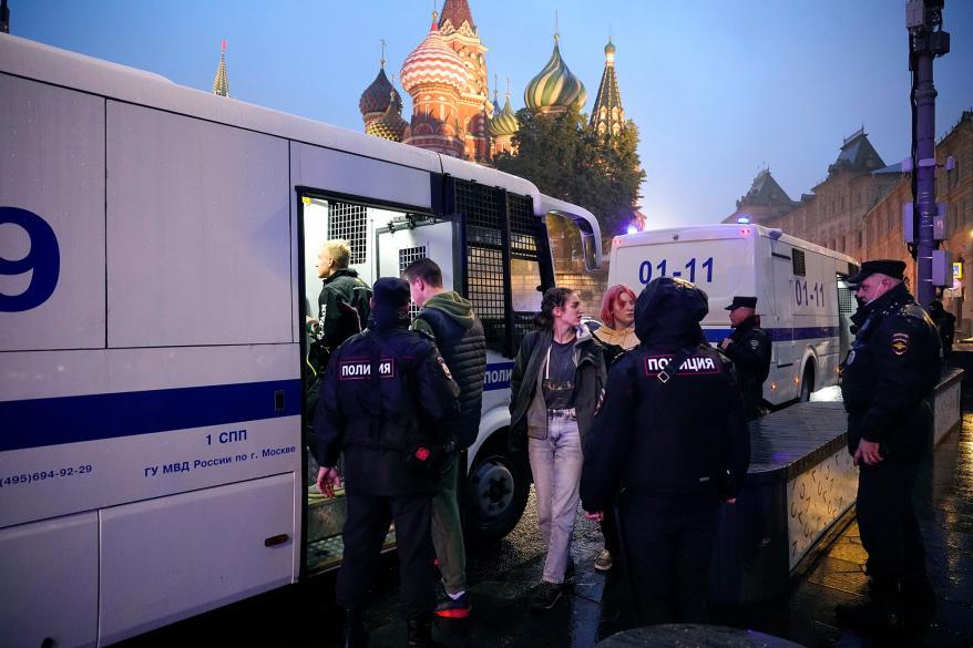 A picture of Russian police escorting detained demonstrators into a police bus.