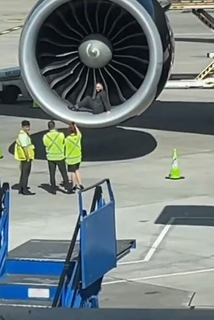 The airline worker appeared to be relishing his moment in front of the camera, striking a series of poses as he sat up against the turbine of the engine. 