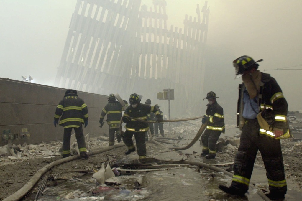 With the skeleton of the World Trade Center twin towers in the background, New York City firefighters work amid debris on Cortlandt St. after the terrorist attacks of Tuesday, Sept. 11, 2001.