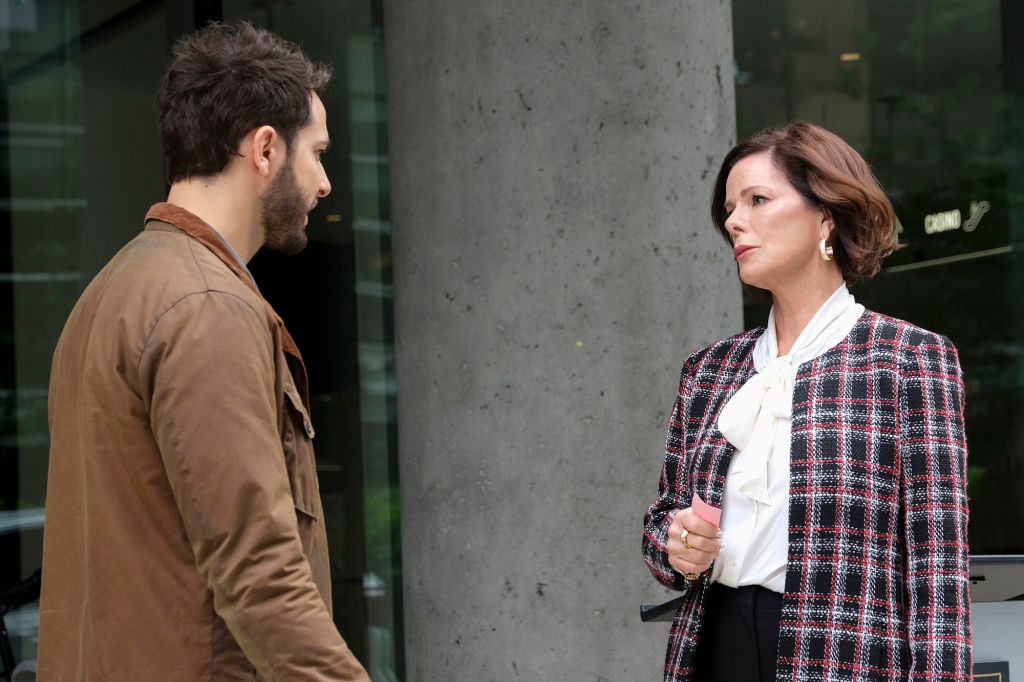 Photo of Astin and Harden as Todd and Margaret. They're standing outside facing each other; Margaret looks very serious. She's wearing a checked jacket and a white shirt; he's wearing a brown coat with a dark brown collar.