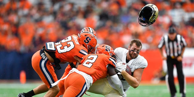 Purdue tight end Payne Durham, right, loses his helmet while being tackled by Syracuse linebacker Marlowe Wax (2) and defensive back Justin Barron (23) during the first half of an NCAA college football game in Syracuse, N.Y., Saturday, Sept. 17, 2022.