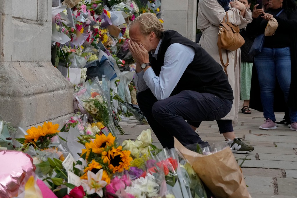 A mourner is overcome with emotion as he pays his respect at the gates of Buckingham Palace in London on Sept. 9, 2022. 