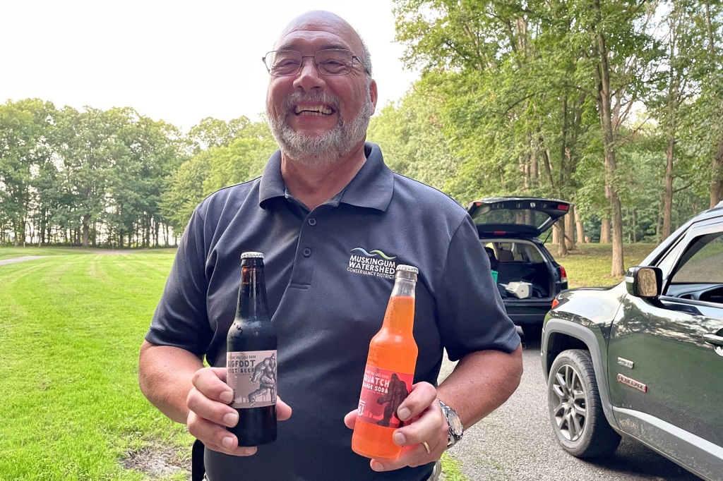 A man holding Bigfoot-themed sodas. 