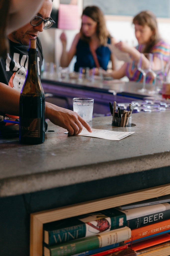 A bartender pouring a glass of wine. 