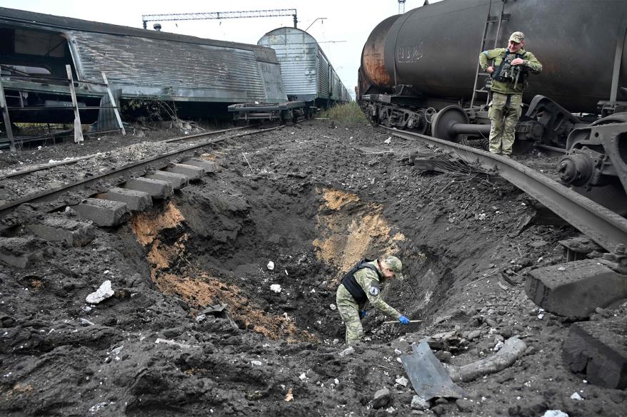 A forensic explosives expert examines a crater from a missile explosion at a freight railway station in Kharkiv on September 21, 2022, amid Russia's military invasion on Ukraine.