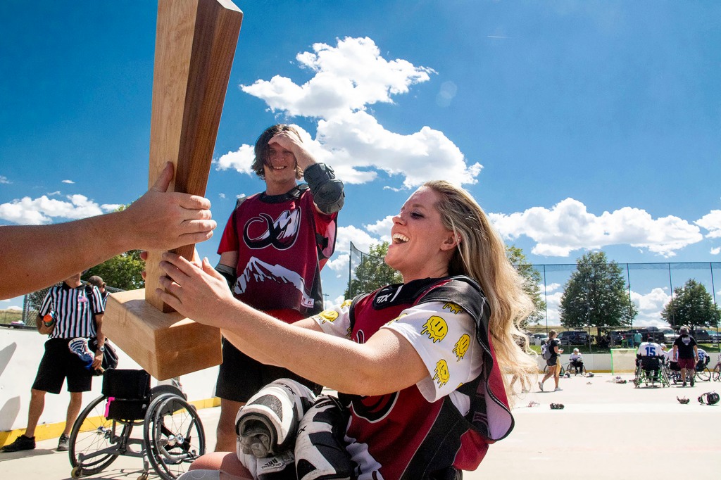 Allison Brown hoists the wheelchair lacrosse national championship trophy after her Colorado Rolling Mammoth defeated the Milwaukee Eagles in Aurora, Colorado on Aug. 27, 2022.