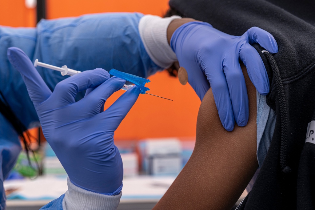 Healthcare worker administering a Pfizer COVID vaccine.