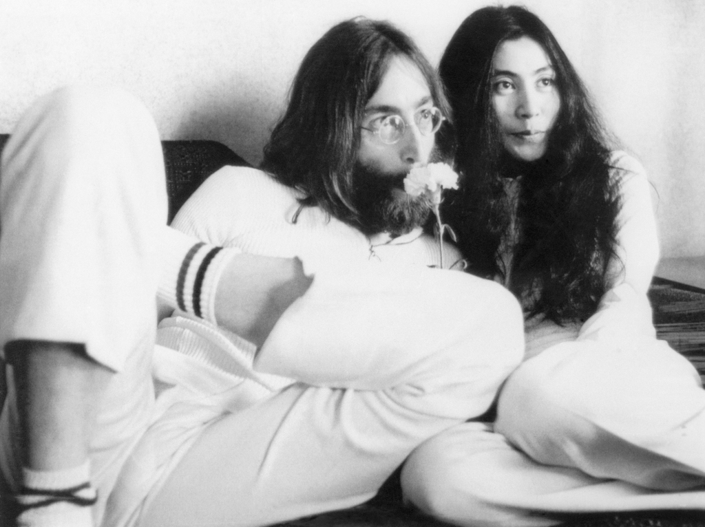 Musician John Lennon and wife Yoko Ono at a press conference from their bed in 1969. The couple announced that they would stay in bed seven days "to conceive a baby in Amsterdam" and called it "a make-love-and-not-war-protest, a happening, a bed production."
