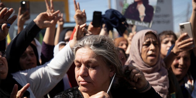 A woman cuts her hair during a protest over the death of 22-year-old Kurdish woman Mahsa Amini in Iran, in the Kurdish-controlled city of Qamishli, Syria Sept. 26, 2022.  