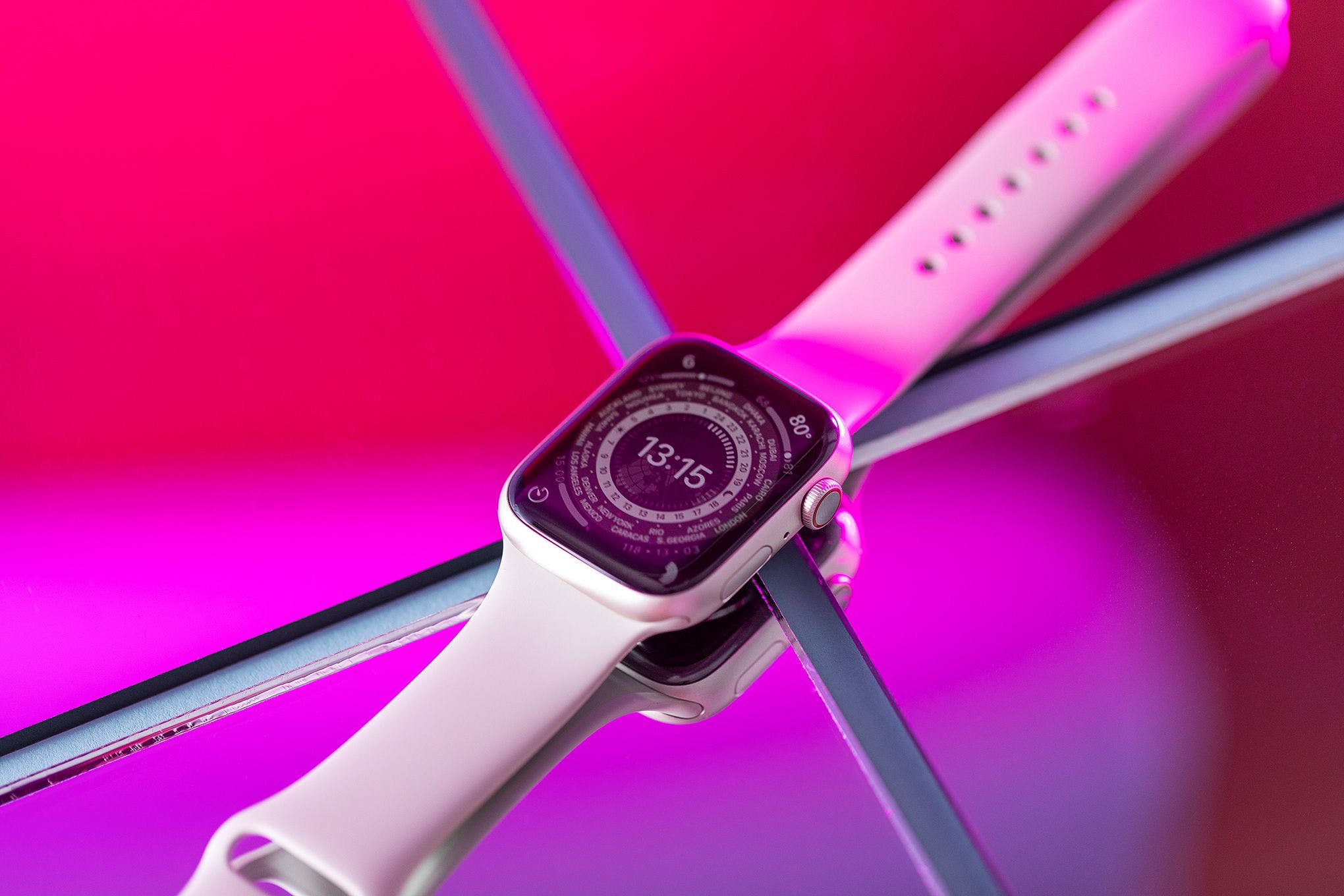 Apple Watch Series 8 with the Lunar face sitting atop a mirror with purple lighting