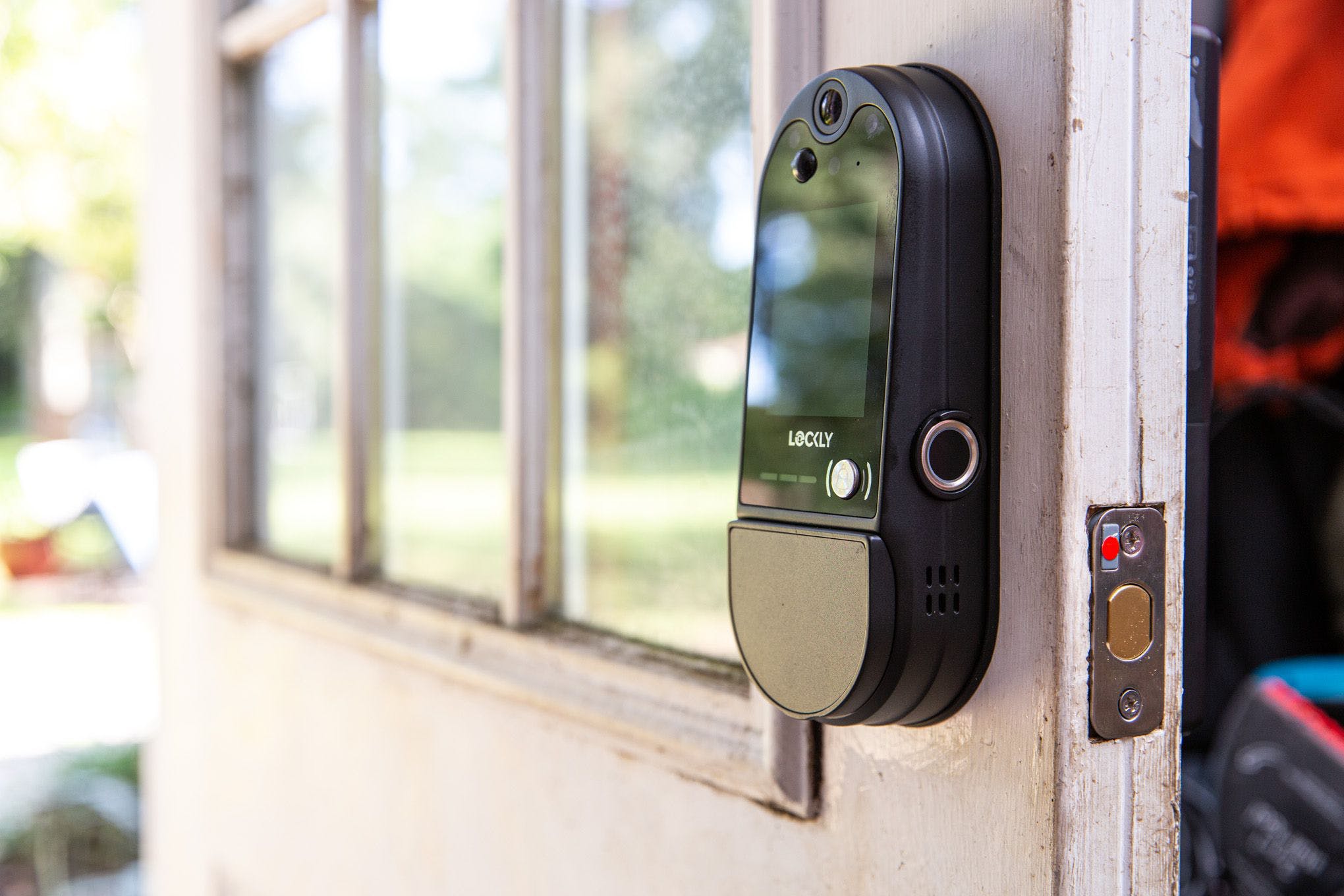 Three-quarters profile shot of the Vision Elite installed on an open door. The deadbolt cover has a red dot indicating the position of the magnetic sensor.