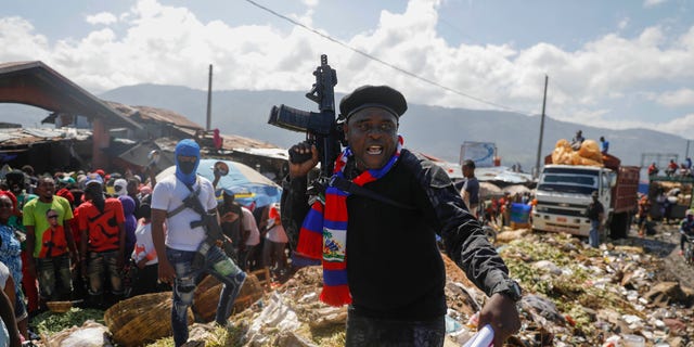 Barbecue, the leader of the "G9 and Family" gang, stands next to garbage in the La Saline neighborhood in Port-au-Prince, Haiti, Friday, Oct. 22, 2021. 