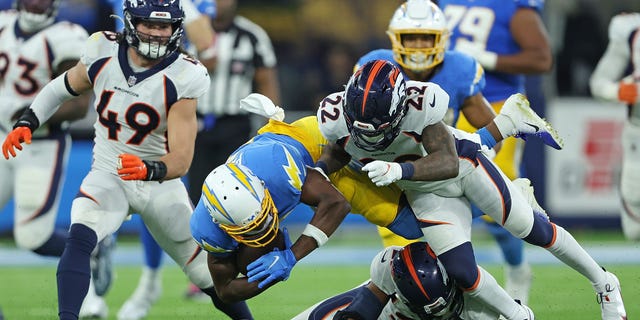 Joshua Palmer, #5 of the Los Angeles Chargers, is brought down by K'Waun Williams, #21, and Kareem Jackson, #22 of the Denver Broncos, during the second half at SoFi Stadium on Oct. 17, 2022 in Inglewood, California.