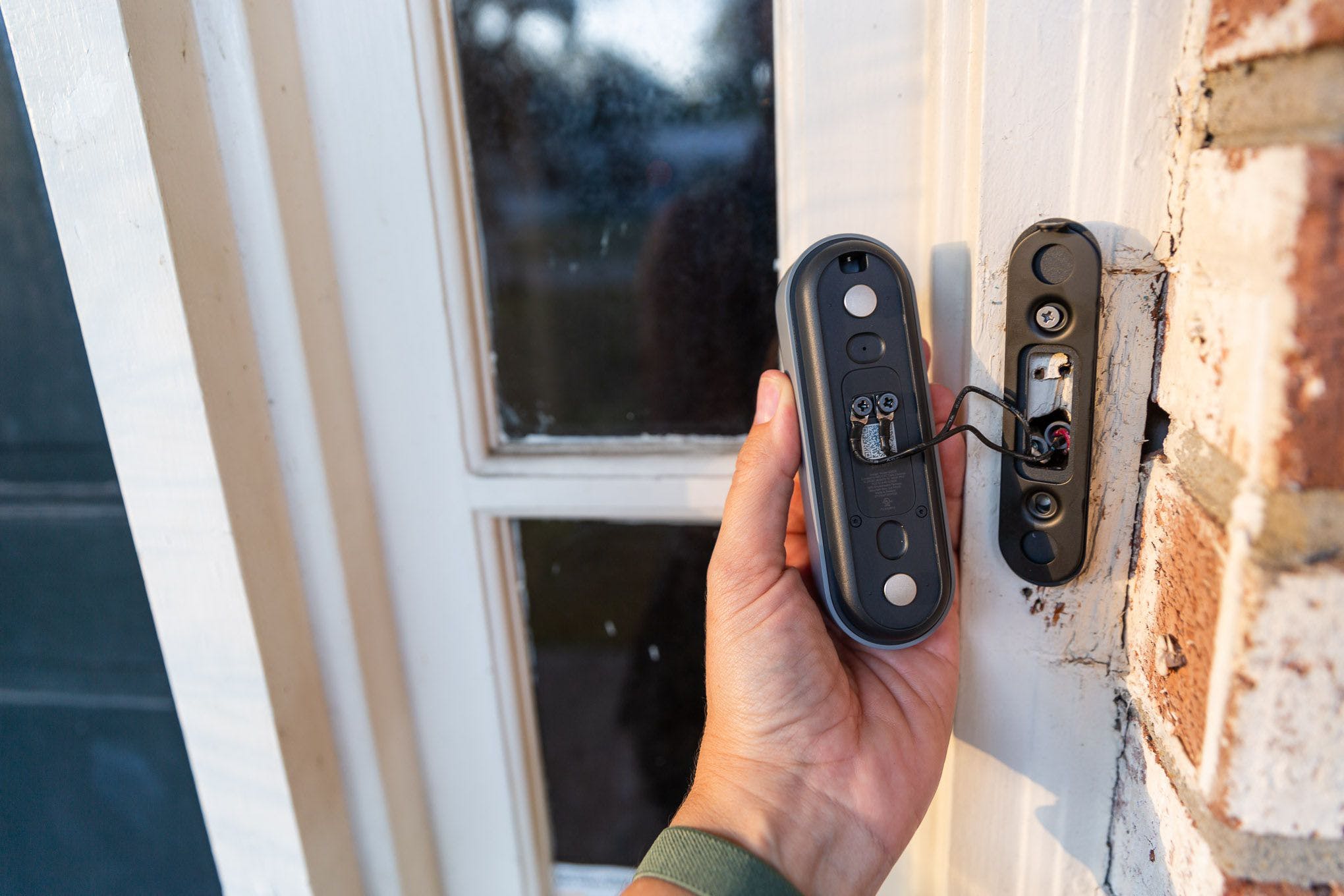 Photo of a hand holding the Nest Doorbell, attached to the wiring harness but detached from the hardware mount