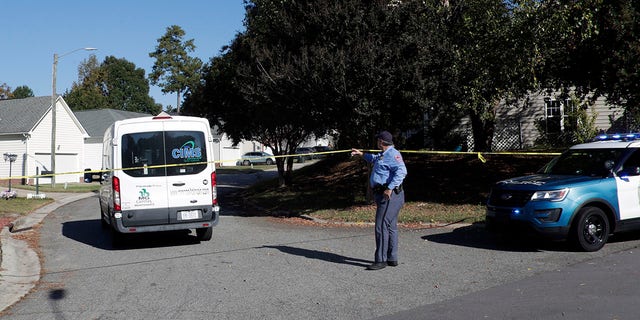 A Raleigh police officer allows a person to return home on Sahalee Way, which remains closed except for residents following a shooting in Raleigh, N.C., seen on Friday, Oct. 14, 2022. 