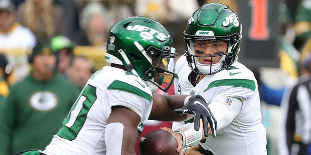 Zach Wilson #2 of the New York Jets hands the ball to Breece Hall #20 during a game against the Green Bay Packers at Lambeau Field on October 16, 2022, in Green Bay, Wisconsin.  The Jets defeated the Packers 27-10. 