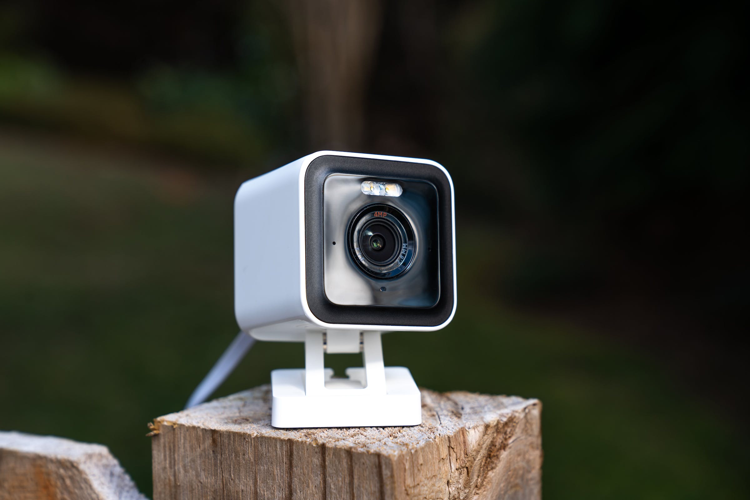 A white camera on a fence pole.