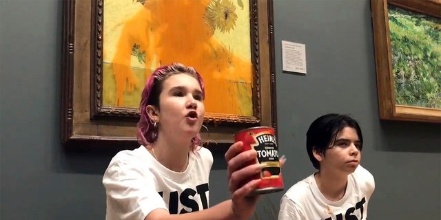 Handout photo issued by Just Stop Oil of two protesters who have thrown tinned soup at Vincent van Gogh's famous 1888 work Sunflowers at the National Gallery in London, Friday Oct. 14, 2022. 