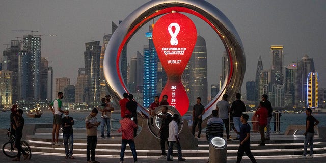 People gather around the official countdown clock showing the remaining time until the kickoff of World Cup 2022 in Doha, Qatar, Nov. 25, 2021. 