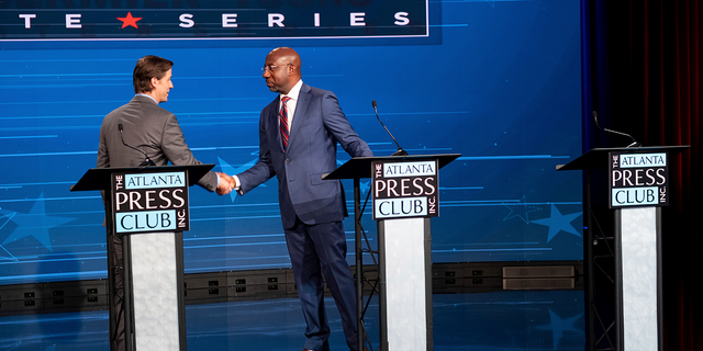 Sen. Raphael Warnock, D-Ga., shakes hands with libertarian challenger Chase Oliver at a Georgia U.S. Senate debate. If Oliver garners just a few percent of the general election vote, he could hold both Warnock and GOP candidate Herschel Walker under 50%, triggering a runoff.