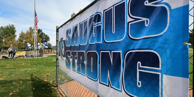 People grieve beside a makeshift memorial in Central Park, not far from Saugus High School on Nov. 15, 2019, in Santa Clarita, California - A teenage boy gunned down fellow students at a California high school on his 16th birthday on Nov. 14, 2019, killing two and wounding another three before turning the pistol on himself.