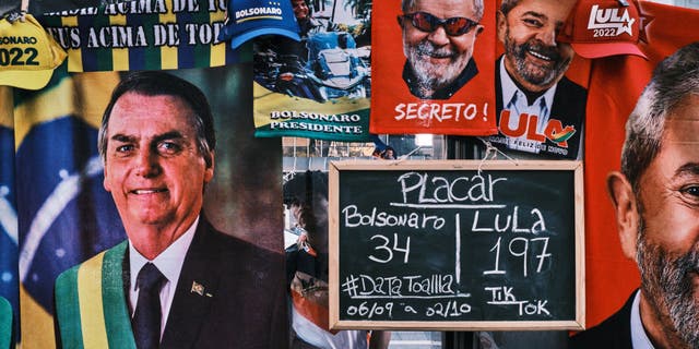 SAO PAULO, BRAZIL - SEPTEMBER 23: A man stands by a street stall selling towels of presidential candidates Luis Inacio Lula da Silva and Jair Bolsonaro at Paulista Avenue on September 23, 2022, in Sao Paulo, Brazil. The stall displays a sign with the number of towels of each candidate sold so far. Brazilians will go to polls on October 30 in the next round of the country's polarized presidential election.  (Photo by Gustavo Minas/Getty Images)