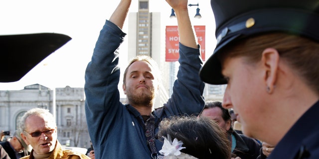 David DePape, center, records Gypsy Taub being led away by police after her nude wedding outside City Hall on Dec. 19, 2013, in San Francisco. DePape is accused of breaking into House Speaker Nancy Pelosi's California home and severely beating her husband with a hammer. DePape was known in Berkeley, Calif., as a pro-nudity activist who had picketed naked at protests against local ordinances requiring people to be clothed in public. 