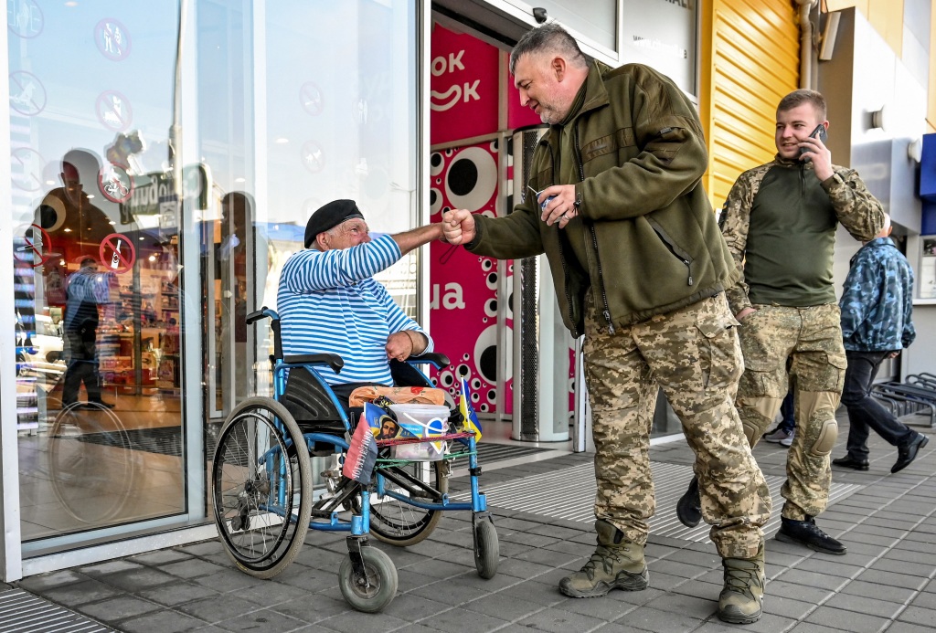 Hryhorii Yanchenko, a Soviet army veteran who fled to Zaporizhzhia from Russian controlled Kherson city, greets service members as he collects donations for the Ukrainian Armed Forces amid Russia's attack on Ukraine, in Zaporizhzhia, Ukraine on Sept. 29, 2022.