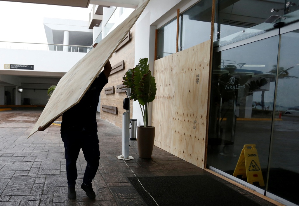 A worker boards up the windows and glass panels of a hotel on the seafront as Hurricane Orlene approaches the Pacific beach resort of Mazatlan on Oct. 2, 2022. 