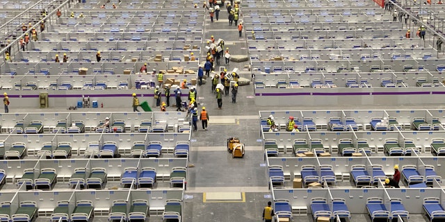 In this photo released by Xinhua News Agency, workers labor at the site of a temporary hospital being constructed at the National Exhibition and Convention Center (Shanghai) in east China's Shanghai, Friday,  April 8, 2022. (Ding Ting/Xinhua via AP)