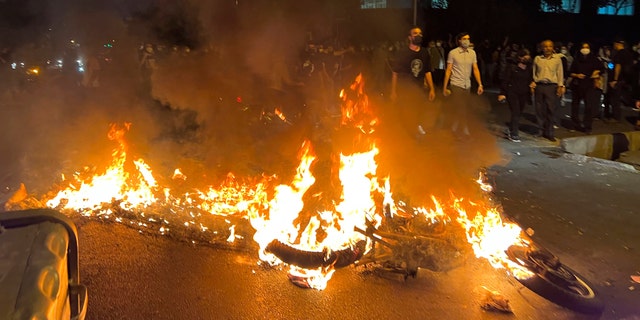 A police motorcycle burns during a protest over the death of a young woman who had been detained for violating the country's conservative dress code, in downtown Tehran, Iran. (AP Photo)